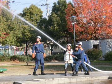 消防職員の手助けのもと、放水訓練を行う女性