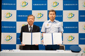 写真：消防長と学長が調印が終わり覚書を披露しています。