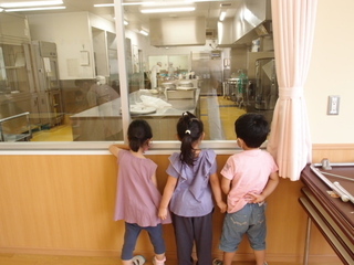 写真:ランチルームから調理室を見る子ども達