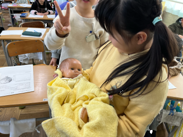 写真：赤ちゃんの人形を抱っこする様子