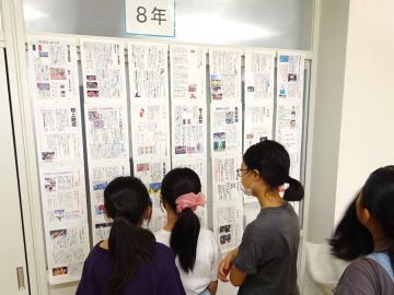 写真：スポーツ新聞とそれを見る児童ら