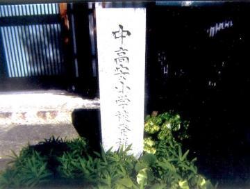 写真: 明治5年(1872年)服部川の光明寺を仮庁舎として創設。明光寺にある小学校発祥の地の石碑