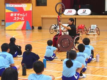 写真：男性がレース用車いすを持ちあげる様子