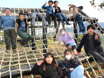写真：アスレチック遊具の上に乗ってポーズを取る児童ら