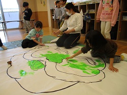 大きな絵に絵の具で色を塗る写真
