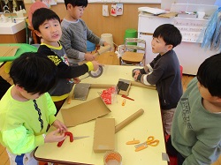ハサミやガムテープを使って劇の小道具を作っている写真