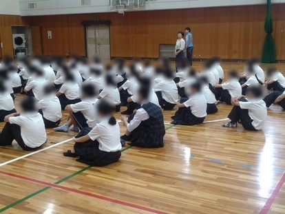 床に座って話を聞く生徒の写真