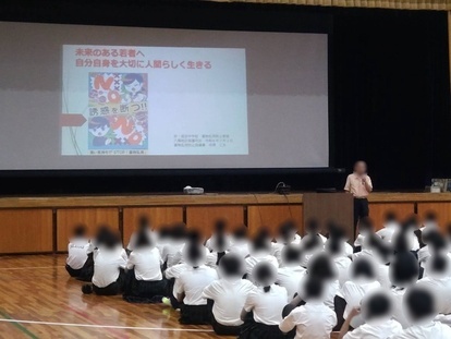 スクリーンと登壇者の話を聞く生徒の写真