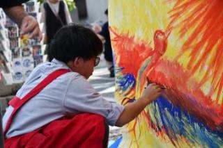 写真：童画家の徳 治昭さんの作品にコラボペイントする学生