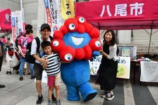 写真：ミャクミャクと記念撮影する家族