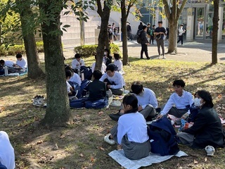 写真：公園内の屋外で昼食をとる学生ら2