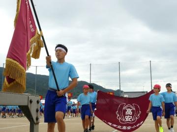 写真：校旗を持って行進する生徒会役員ら