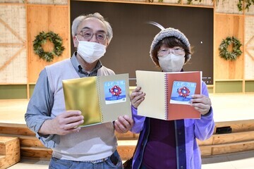 写真：手作りノートを開いて微笑む夫婦