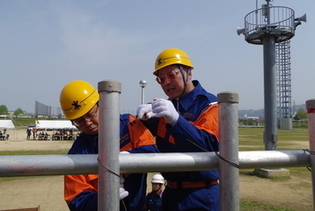 消防団員が土手に杭をさして番線を使用して杭と杭を止めています