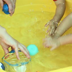 水遊びでたらいに手を入れる写真
