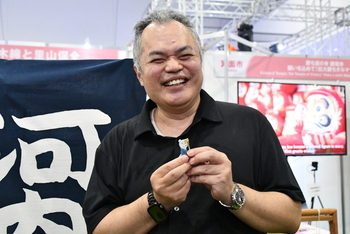 河内木綿を糸にしたものを巻き付けたストラップを手に笑顔の男性