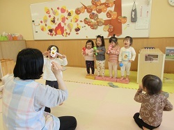 保育室のステージでマイクをもって歌う写真