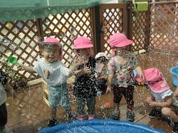 子どもが園庭で水遊びをしています