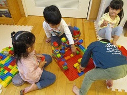 友だちと一緒にブロックでお家つくりをする写真