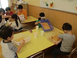 箱の上で絵具をつけたどんぐりを転がして模様をつけて遊ぶ写真