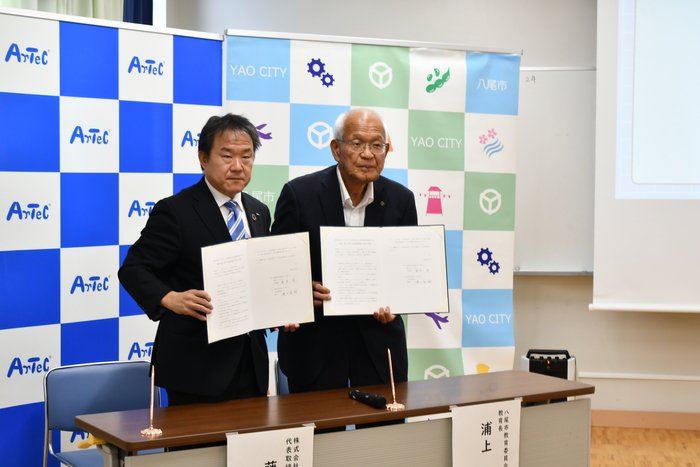 調印の証として、署名された覚書を報道関係者に見せている写真