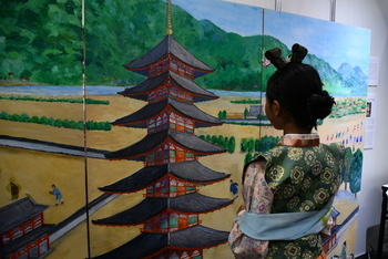 古代衣装着用体験する少女の後ろ姿と由義寺の絵画