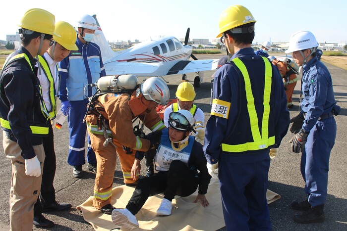 救難隊によって事故機内から救出された負傷者を搬送する