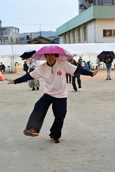 帽子のような傘をかぶって踊る男性