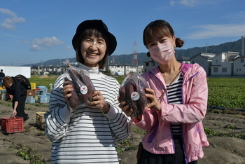 袋詰めしたさつまいもを持つ女性二人