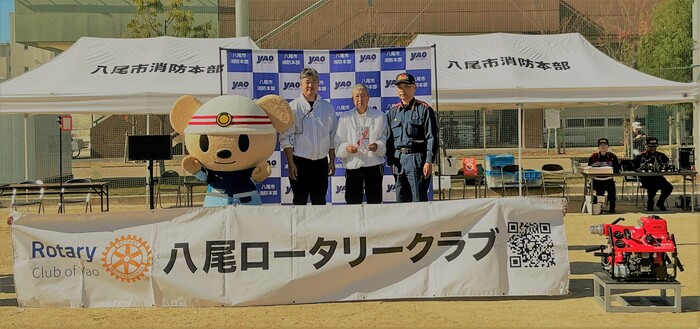 ロータリークラブ様と消防長と寄贈キャラクターの写真