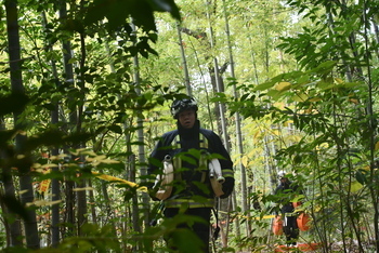 山中を機材を運びながら登る消防職員