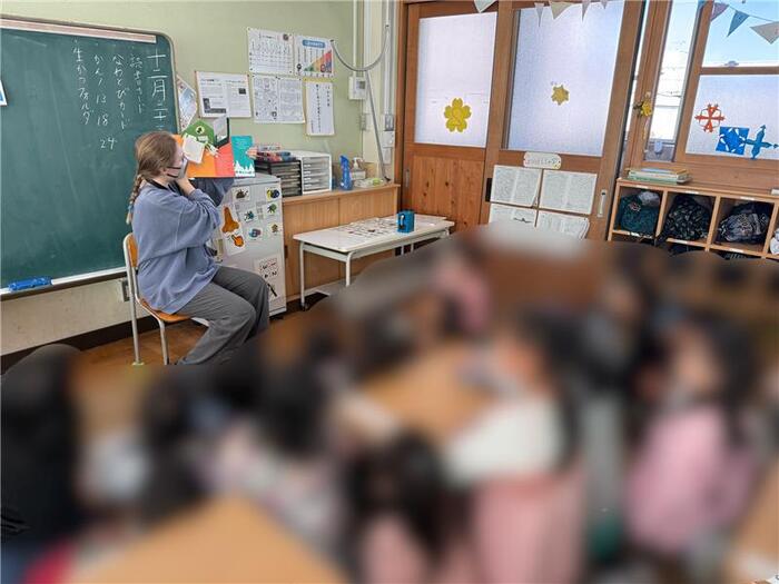 クリスマスの絵本の読み聞かせを聞く児童