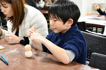 雪だるまに顔などを書く男の子