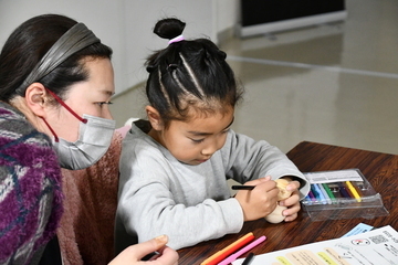 雪だるまに顔などを書く親子