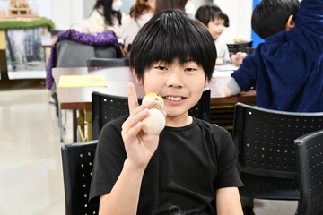 完成した雪だるまを持ちポーズを取る男の子