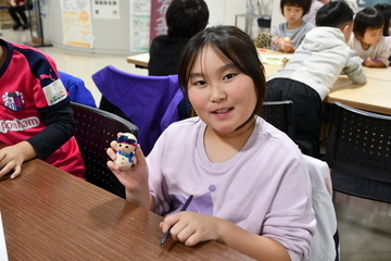 完成した雪だるまを右手に持つ女の子
