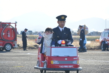 バッテリーカーの消防車に乗って手を振る園児