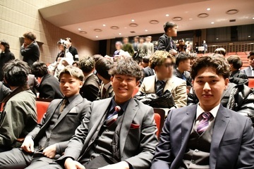 式典会場で並んで座る男性3人