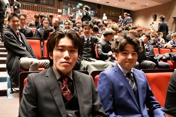 式典会場で並んで座る男性2人