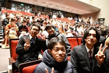 式典会場で2列に並んで座る男性4人