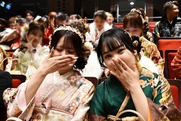 式典会場で口付近に手でポーズをとる女性2人