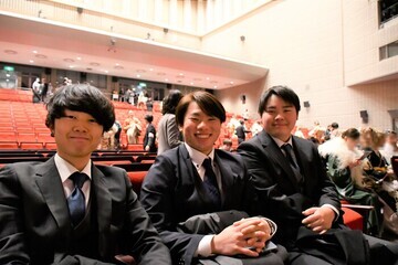 式典会場で座る男性3人