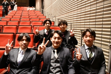 式典会場で2列に並んで座る男性5人