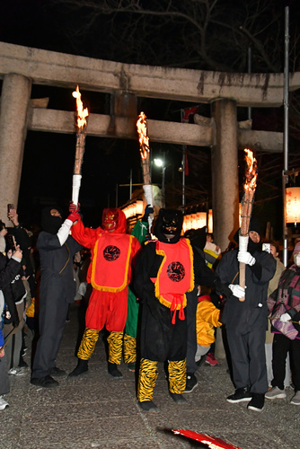 鳥居の前で松明を掲げる3人の鬼