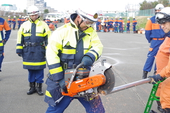 団員がエンジンカッターで単管を切断しています