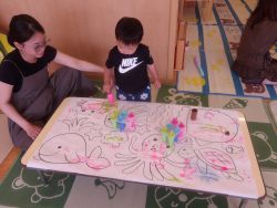 色のついた氷で模造紙におえかきをしている親子の姿