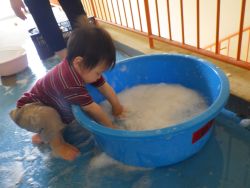 たらいに作った泡を触って楽しむ子どもの姿