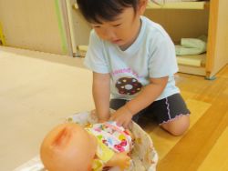 赤ちゃん人形のお世話をする子どもの写真