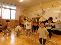保育室の中で新聞を破って楽しむ子どもたちの様子。