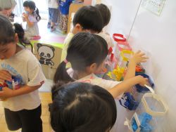 ペットボトルとフラワーペーパーで作ったドリンクバーの装置で子どもたちが遊んでいる写真